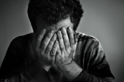A person sits with their head in their hands, suggesting feelings of stress or sadness an emotion often addressed through Bereavement counselling.