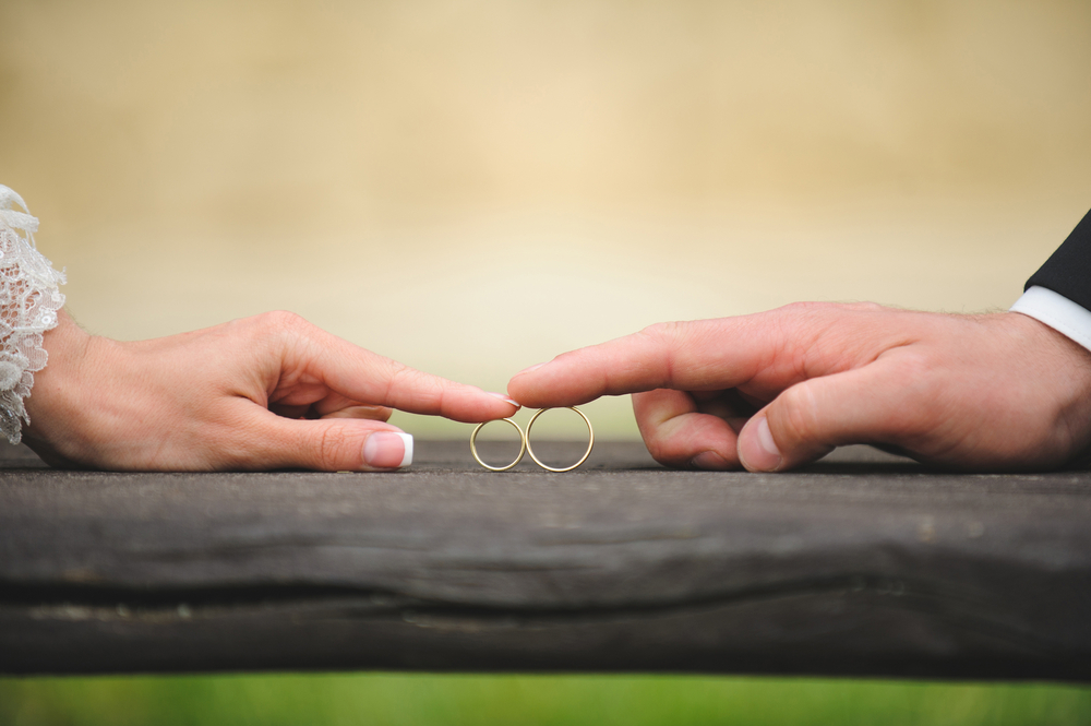 A close-up of a bride and groom’s hands gently touching symbolising the unity fostered through pre-marital counselling.